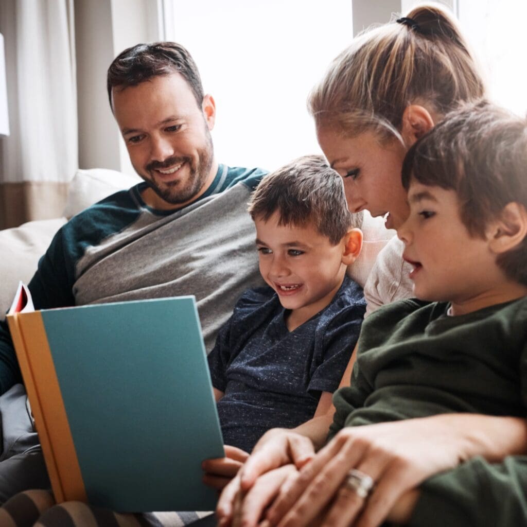 Parents reading a book with their two children, illustrating early childhood support and family engagement for children experiencing homelessness.