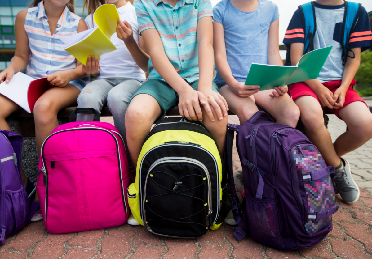 Children holding their backpacks outside of school